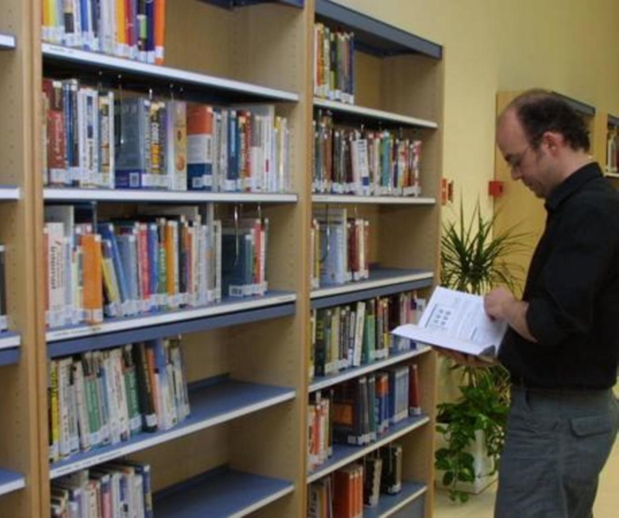 Una persona consulta uno de los libros de la biblioteca. 