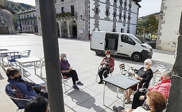 Imagen principal - Tere, Nekane, Asun, Kontxi, Eugenia, Kontxi y Mari Jose toman un café en la plaza del Ayuntamiento de Berastegi. Jaione Ollo trabaja en la farmacia. Naiara Astibia atiende en su peluquería en Berastegi.