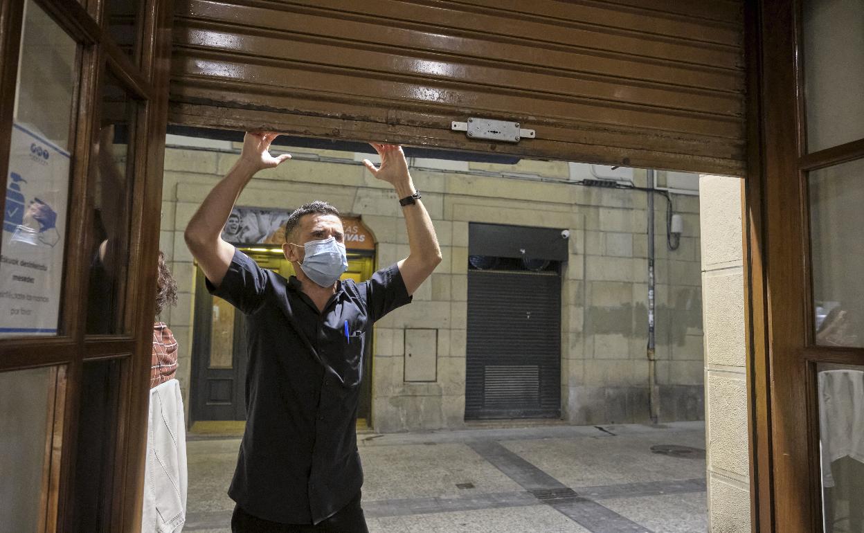 Un hostelero baja la persiana de su negocio en la Parte Vieja de Donostia. 