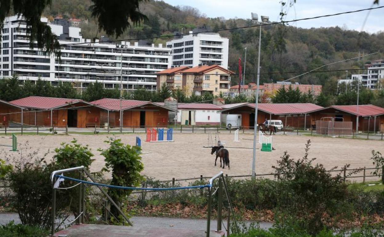 Un niño monta a su caballo ayer en los terrenos de la Hípica de Loiola, con el nuevo barrio de Txomin al fondo, al otro lado del río Urumea.