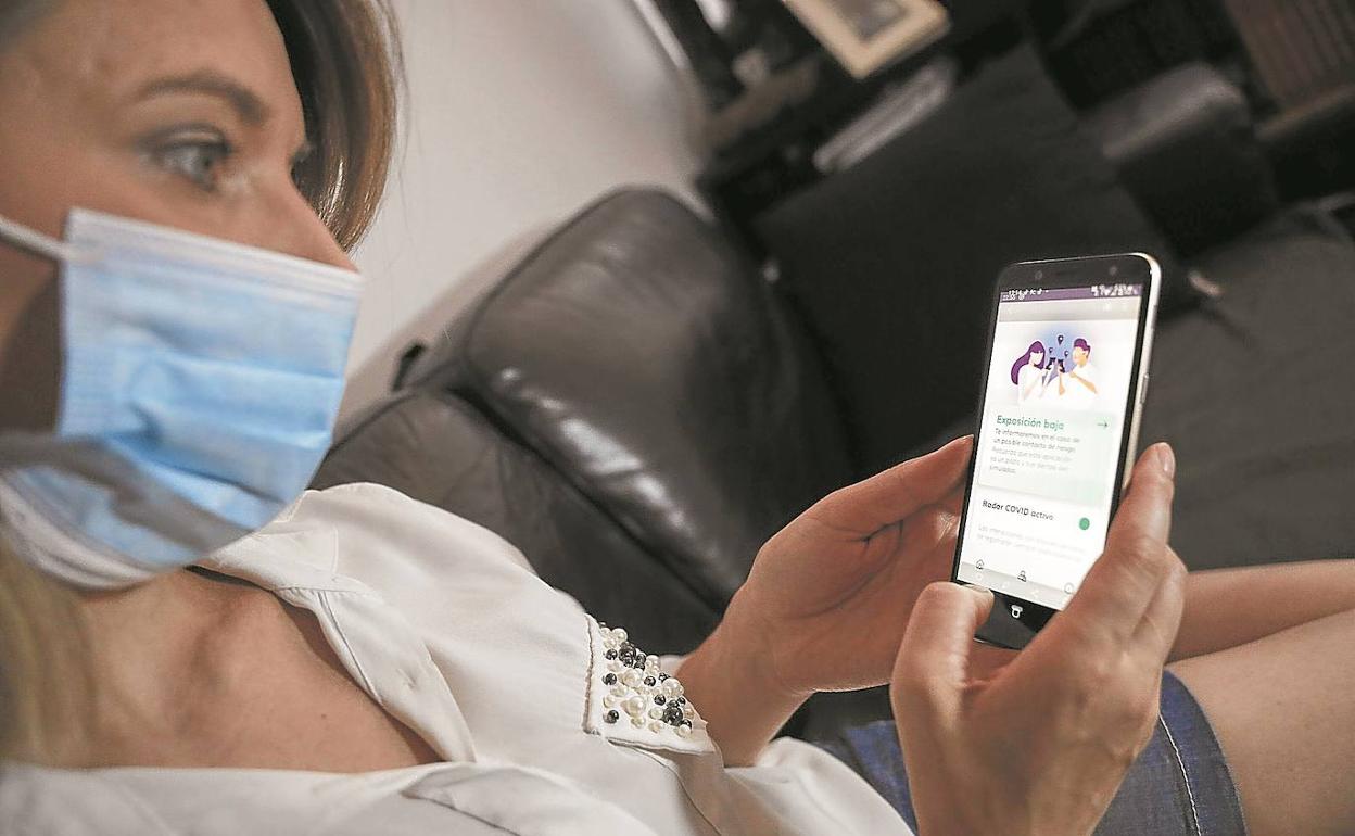 Una mujer hace uso desde su teléfono móvil de la aplicación Radar Covid, que permite rastrear de forma anónima los contactos de un usuario que ha dado positivo en coronavirus. 
