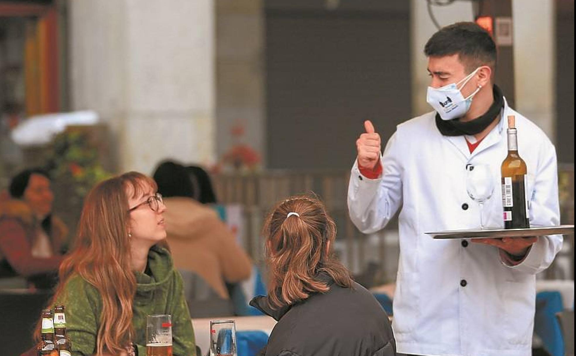 Madrid. Un camarero saluda a dos clientas en terraza. 