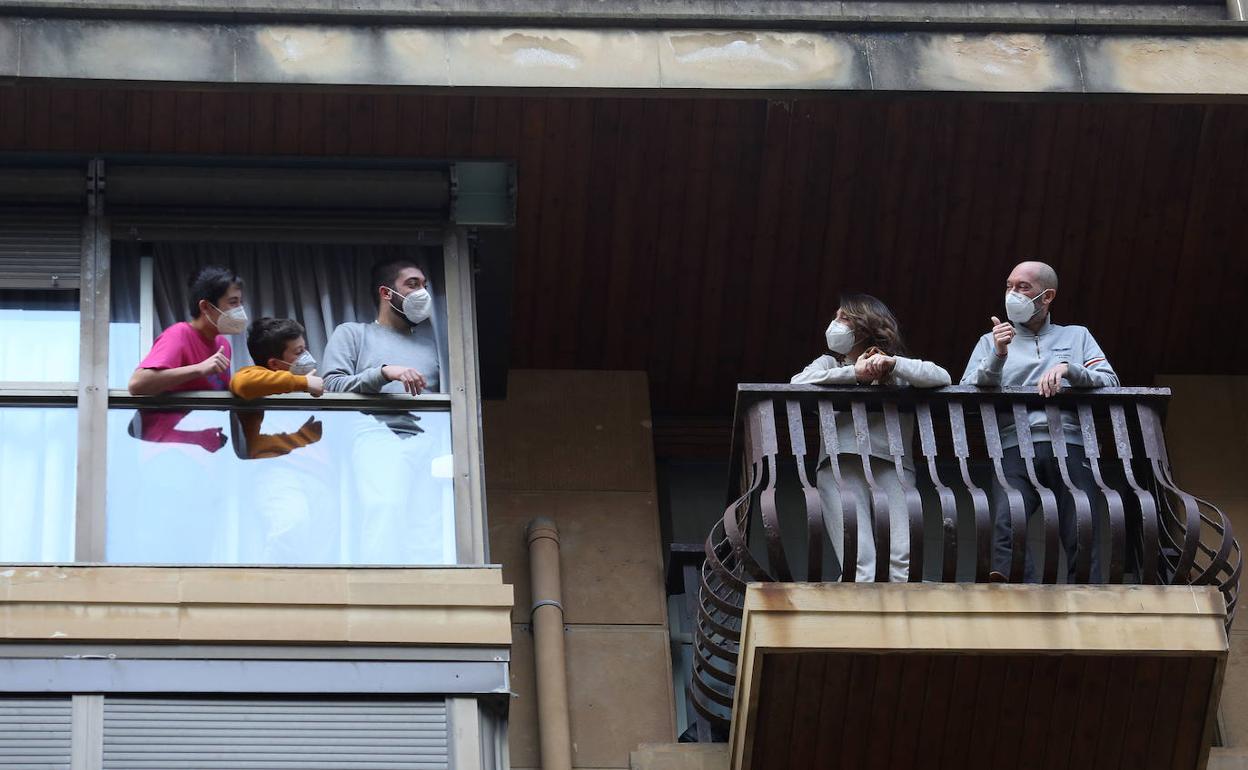 La familia Duran Sagastuma se saluda desde dos ventanas de su casa. Los tres hijos son positivo y los padres negativo.