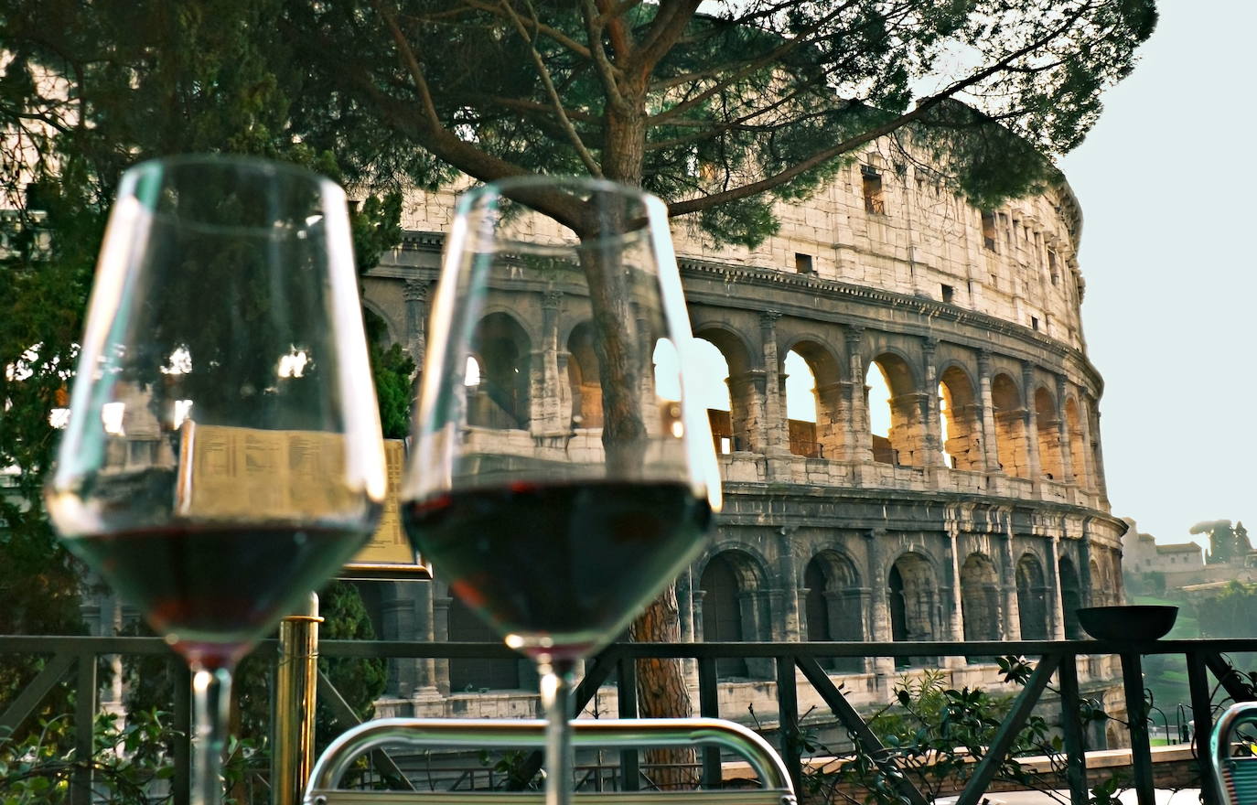 Dos copas de vino con el coliseo romano de fondo.