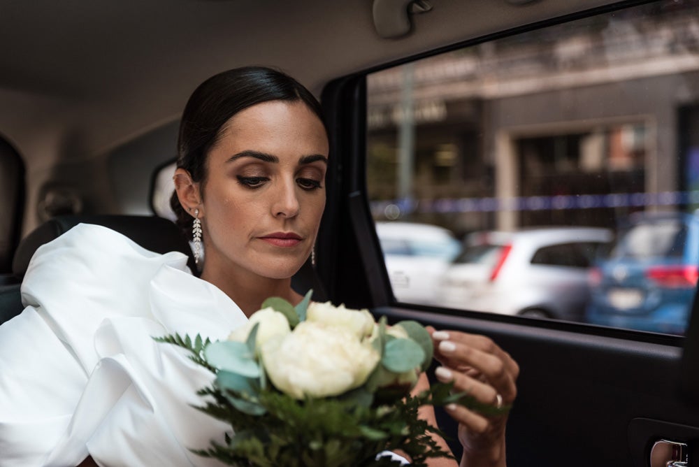 María y Jorge se casaron en Gorliz en una ceremonia íntima adaptada a las circunstancias. De largura 'mini' por encima de la rodilla, con corte asímetrico, volumen en la parte superior y lazadas laterales, la protagonista se ha convertido en una de las novias más impresionantes de las últimas semanas. El diseño lo ha firmado Fabio Encinar, uno de los diseñadores con sede en Madrid más de moda. En cuanto al peinado, otro de los elementos más destacados del estilismo, ha optado por un acertado moño bajo de bailarina súper pulido y tirante, con horquillas de Oui Novias