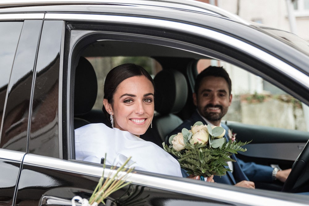 María y Jorge se casaron en Gorliz en una ceremonia íntima adaptada a las circunstancias. De largura 'mini' por encima de la rodilla, con corte asímetrico, volumen en la parte superior y lazadas laterales, la protagonista se ha convertido en una de las novias más impresionantes de las últimas semanas. El diseño lo ha firmado Fabio Encinar, uno de los diseñadores con sede en Madrid más de moda. En cuanto al peinado, otro de los elementos más destacados del estilismo, ha optado por un acertado moño bajo de bailarina súper pulido y tirante, con horquillas de Oui Novias