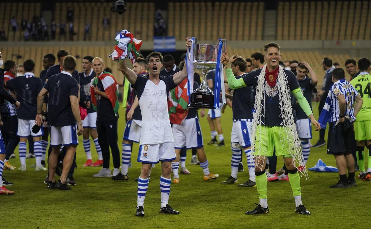 Aritz Elustondo y Álex Remiro, con la red de la portería de recuerdo, sujetan la Copa en las celebraciones tras el pitido final. 