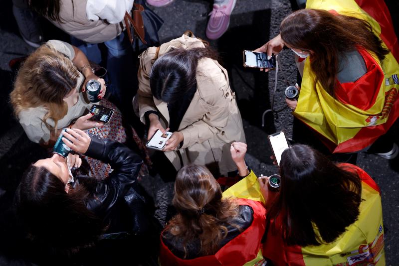 Varios jóvenes siguen el recuento electoral desde sus teléfonos móviles.