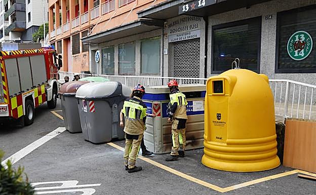 Dos bomberos inspeccionan uno de los contenedores calcinados. 