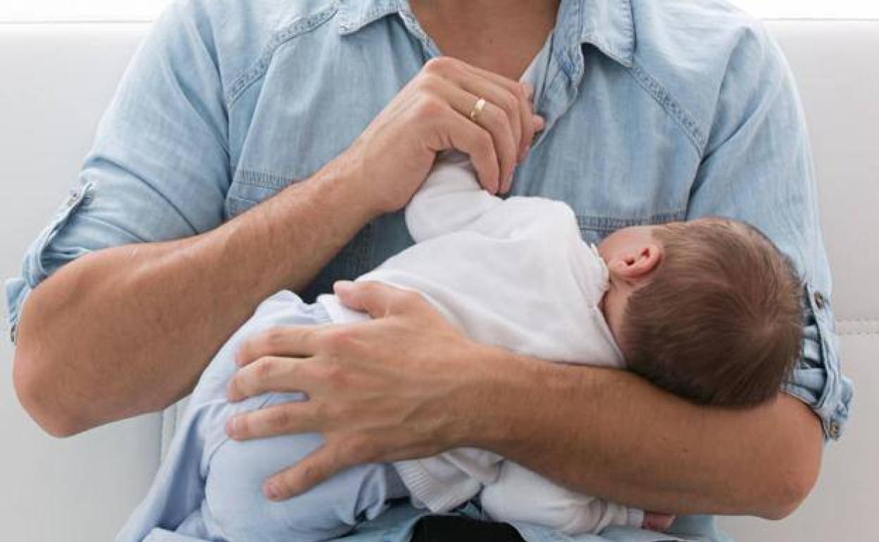 Un padre sostiene a su bebé en brazos. 