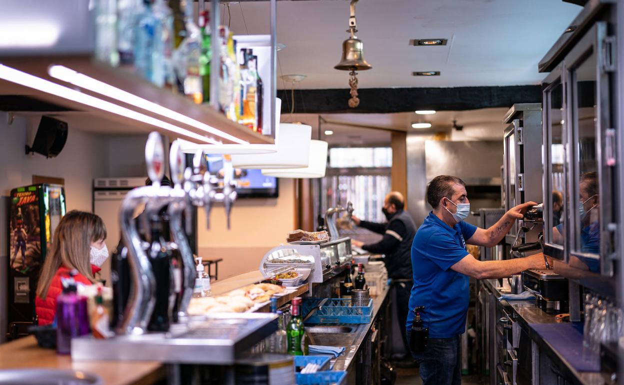 Un camarero atiende a una cliente en un bar. 