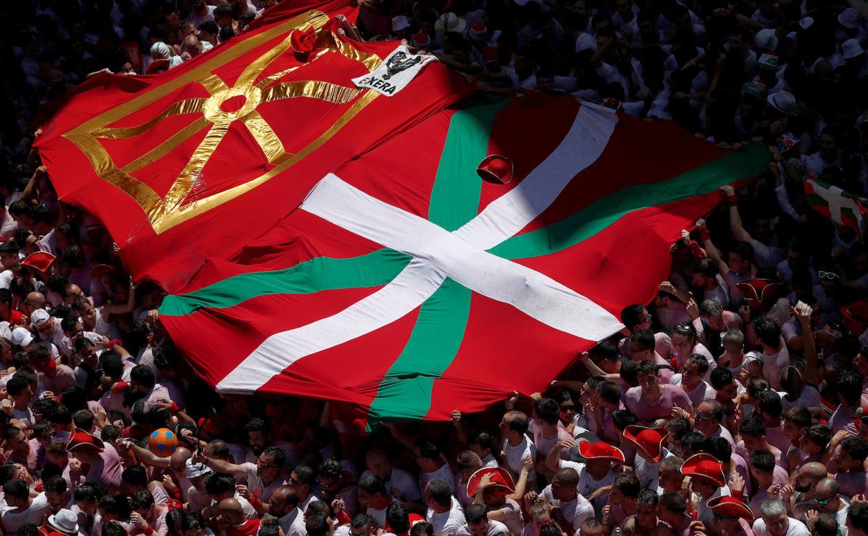 Una multitud sujeta una bandera navarra y una ikurriña en el 'txupinazo' de San Fermín de 2019.