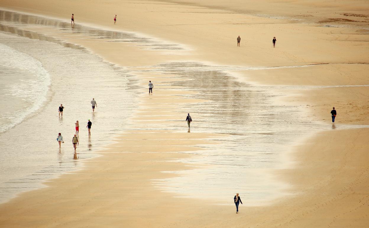 Ciudadanos de paseo a primera hora en la playa de La Concha.