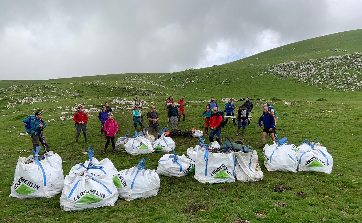 El grupo de voluntarios posa junto a las sacas de basura que han extraído de la sima.
