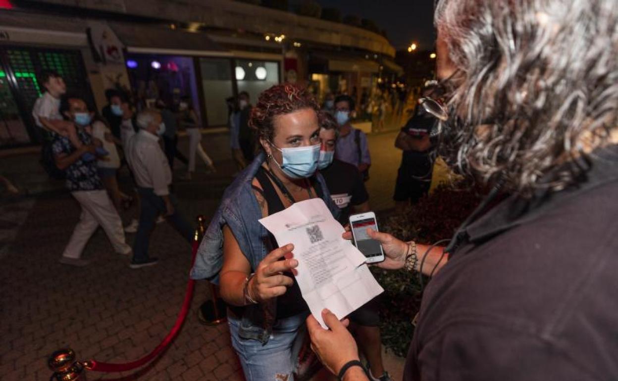 Una mujer muestra un certificado con sus vacunas en regla para acceder a un local en Sansenxo. 