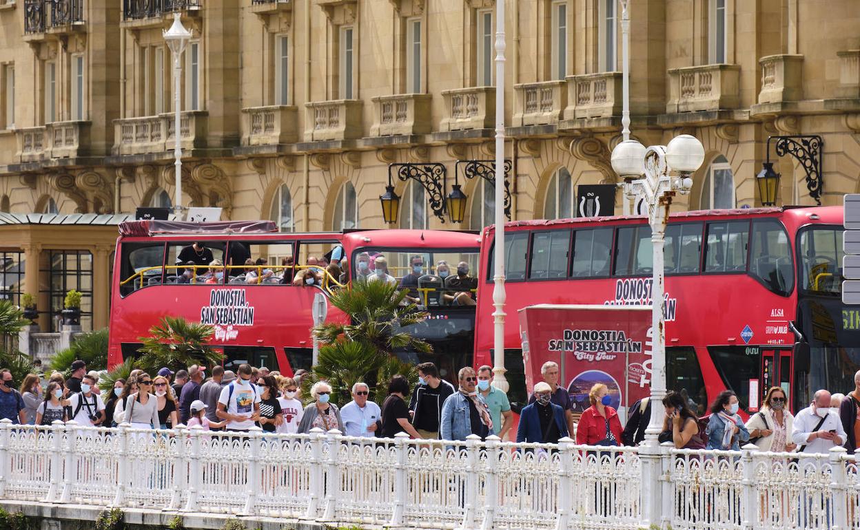 Un grupo de turistas camina junto al bus turístico en el paseo de la República Argentina, ayer en Donostia.