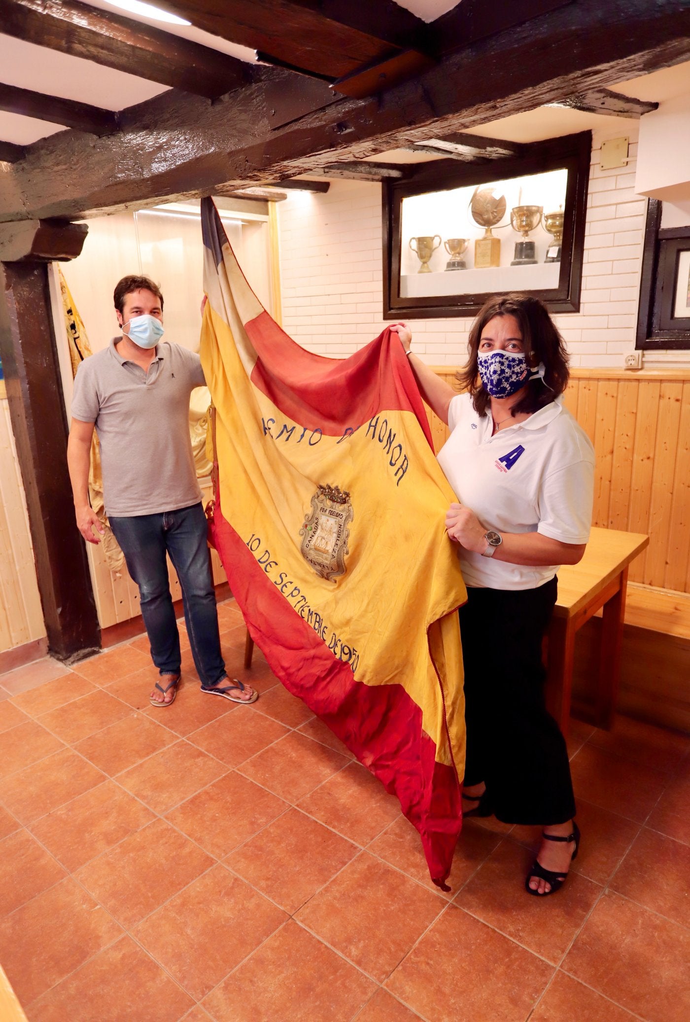 Jaime Herrán (La Esperanza) e Itziar Eguren (Arraun Lagunak), con la bandera de La Concha conquistada en 1950 y que se guarda en la sede de la sociedad, en la Parte Vieja. 