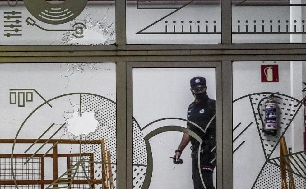 Foto:Un agente de la Ertzaintza revisa los cristales rotos por los disparos. 