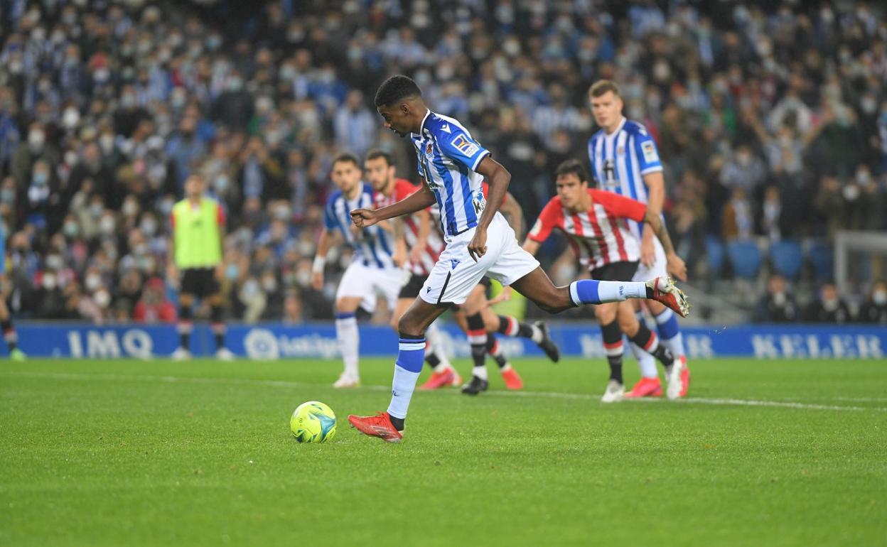 Isak se dispone a lanzar el penalti que supuso el 1-0 en su partido 100 con la Real. uAdnan Januzaj intenta regatear a Iñigo Lekue ayer en el Reale Arena. 