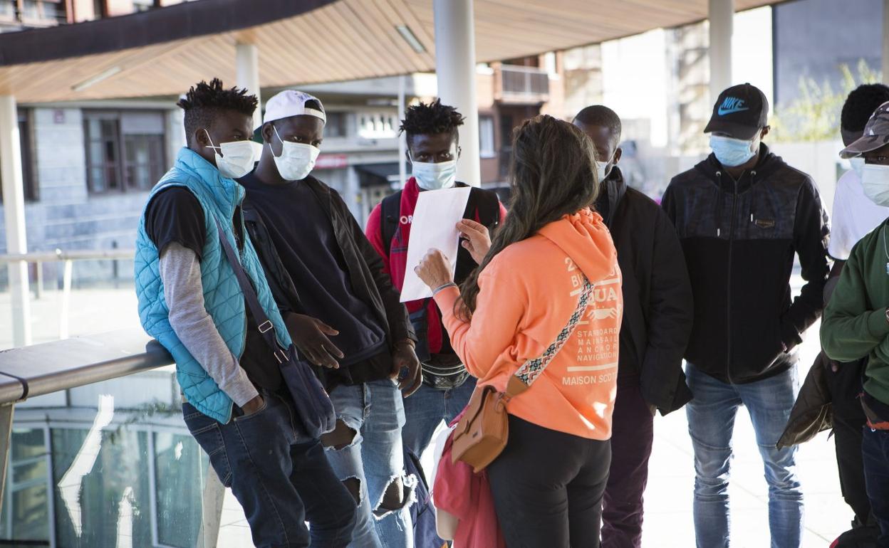 Varios migrantes atienden a las explicaciones que una voluntaria de Irungo Harrera Sarea les da en la plaza San Juan. 