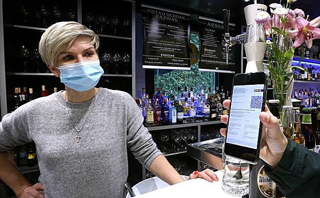 Iana Aculova, de Bukoi taberna, observa el pasaporte Covid, que ya mucha gente tiene descargado en el móvil y será obligatorio en el ocio nocturno. 