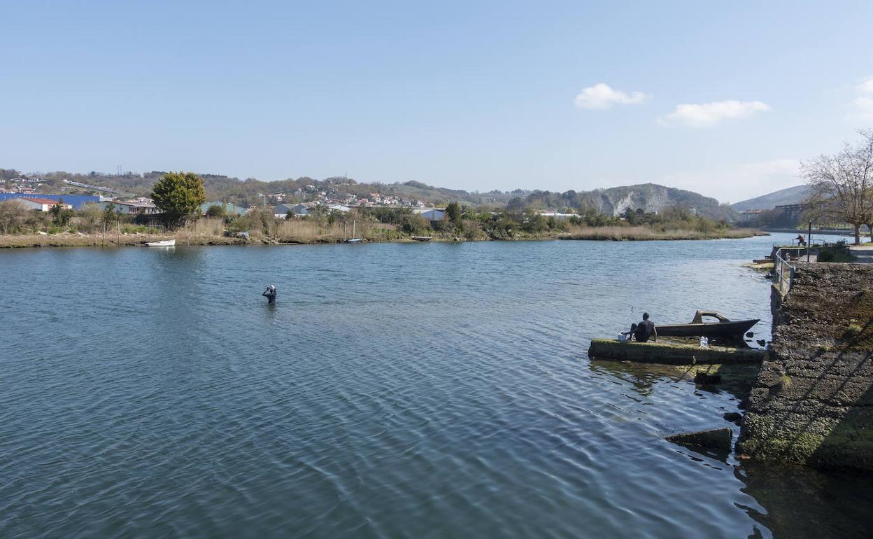 Un migrante observa como otro intenta cruzar el río Bidasoa a la altura de Azkenportu. 