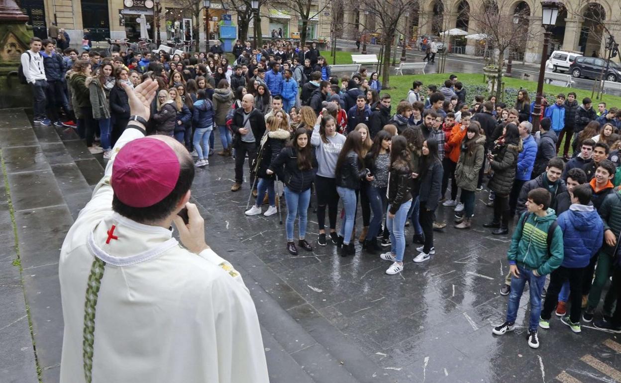 Un grupo de jóvenes, en el exterior de la catedral del Buen Pastor, escucha al obispo Munilla. 