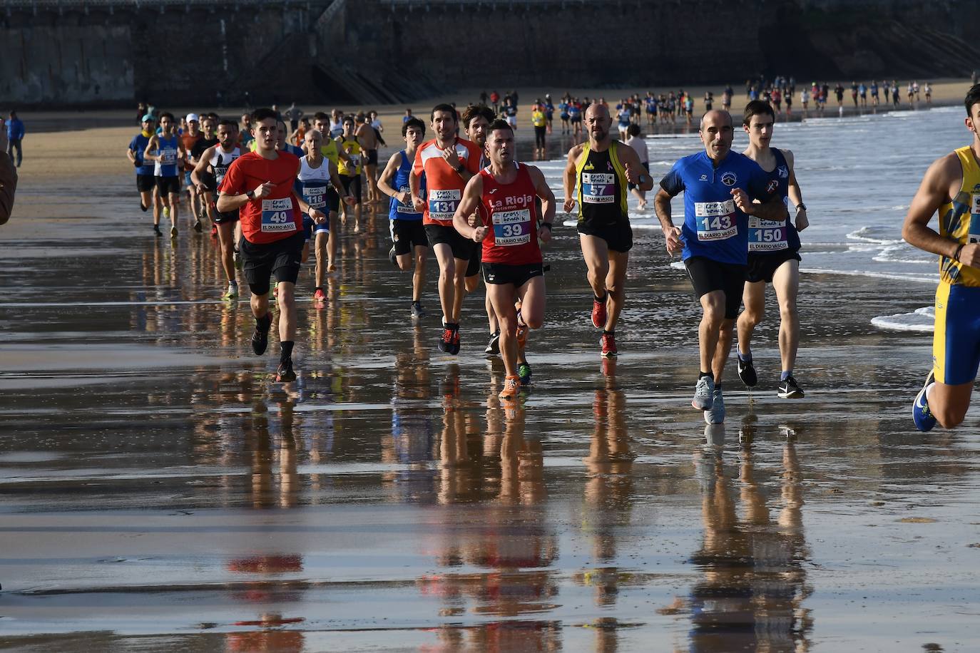 Decenas de atletas corren por la orilla de la playa de La Concha.
