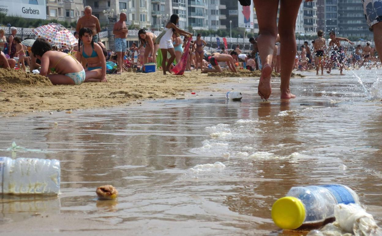 Restos de basura acumulados en la orilla de La Concha en un día de verano con gran afluencia de gente. 