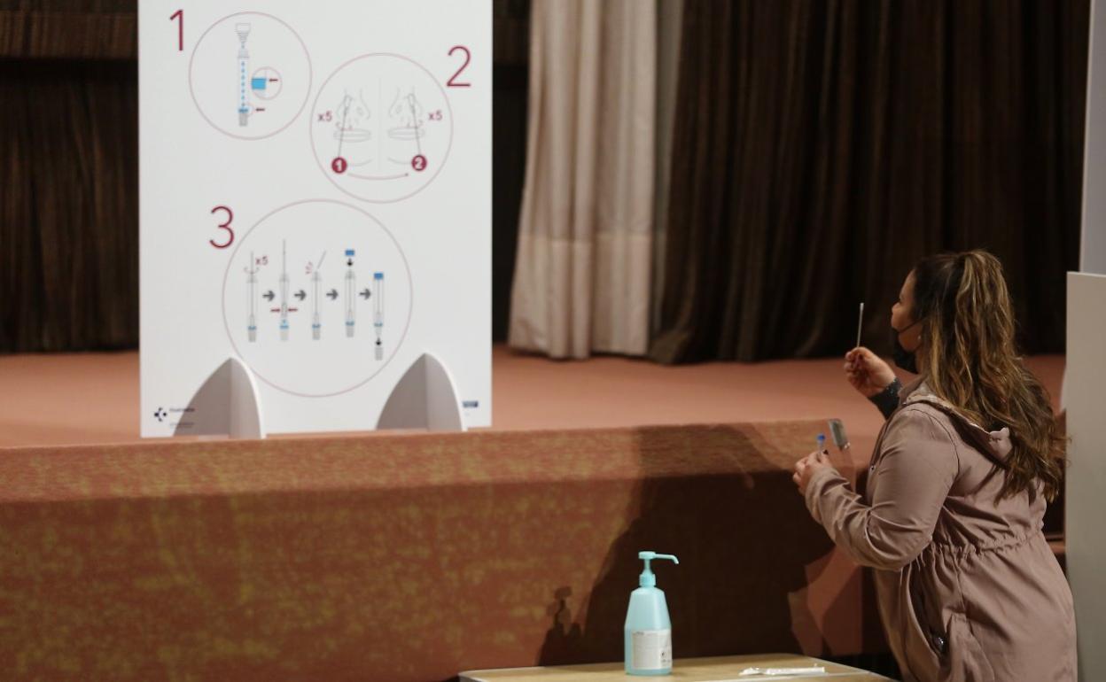 Una joven sigue las instrucciones para el autotest en un panel colocado en el local de Andia. 