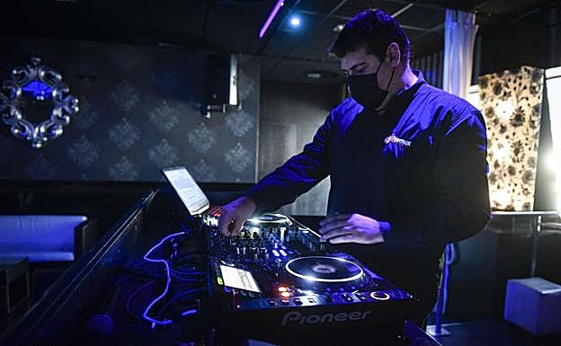 qUn DJ pincha música en un local vacío, antes del horario de cierre a la una de la madrugada. 