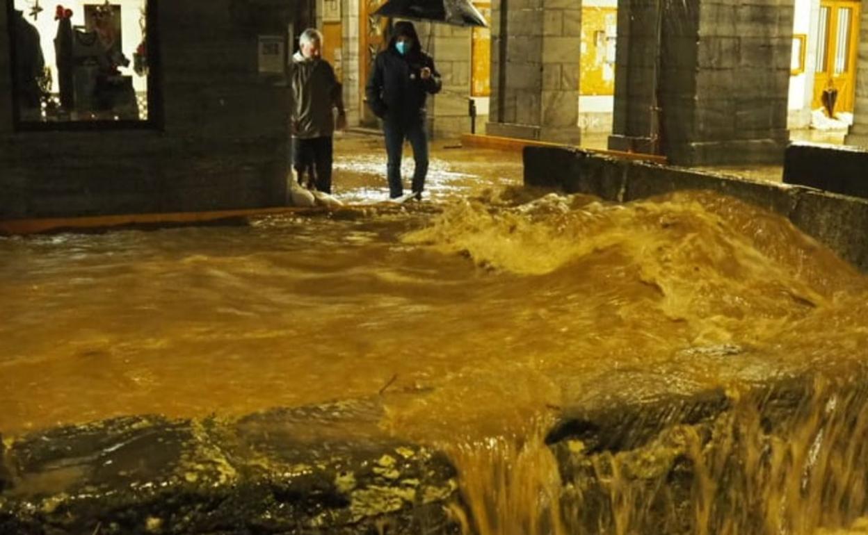 El río Onin desbordado a su paso por el centro de la localidad. 