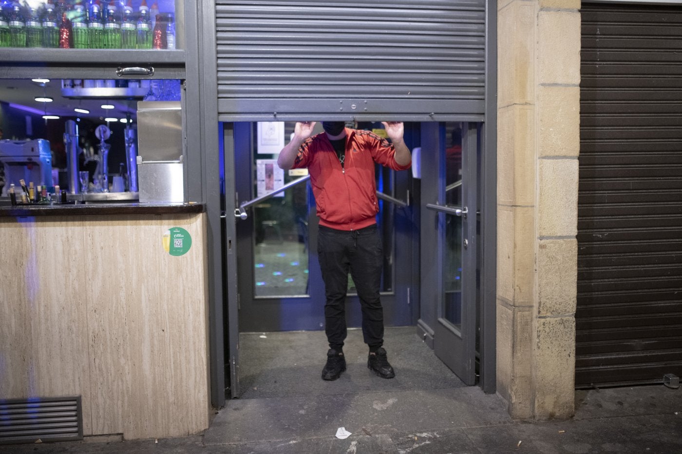 Un hostelero baja la persiana de su bar a la 1.00. El cierre del ocio nocturno se mantiene dos semanas más. 