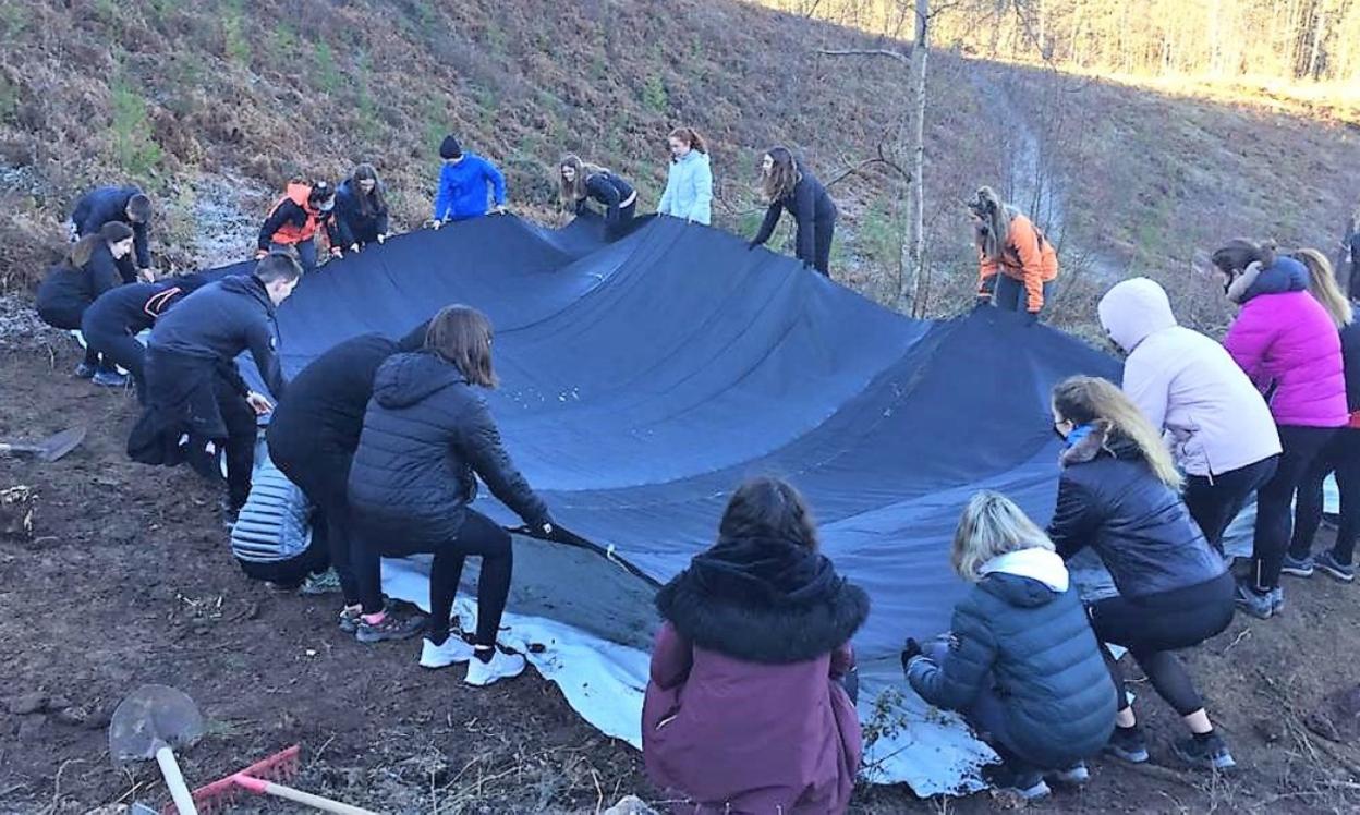 Colocando la impermeabilización de la zona que albergará la masa de agua del humedal. 