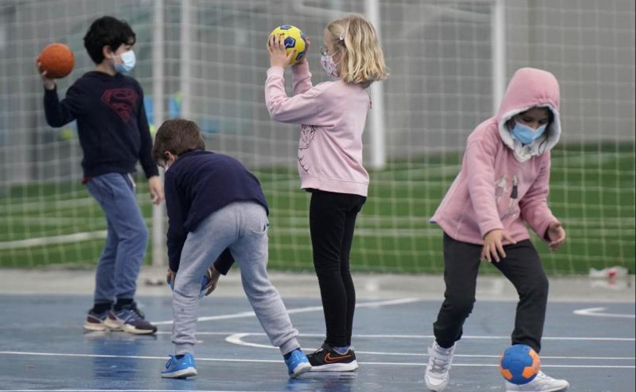 Varios niños juegan con unas pelotas en el patio de un colegio de Donostia.