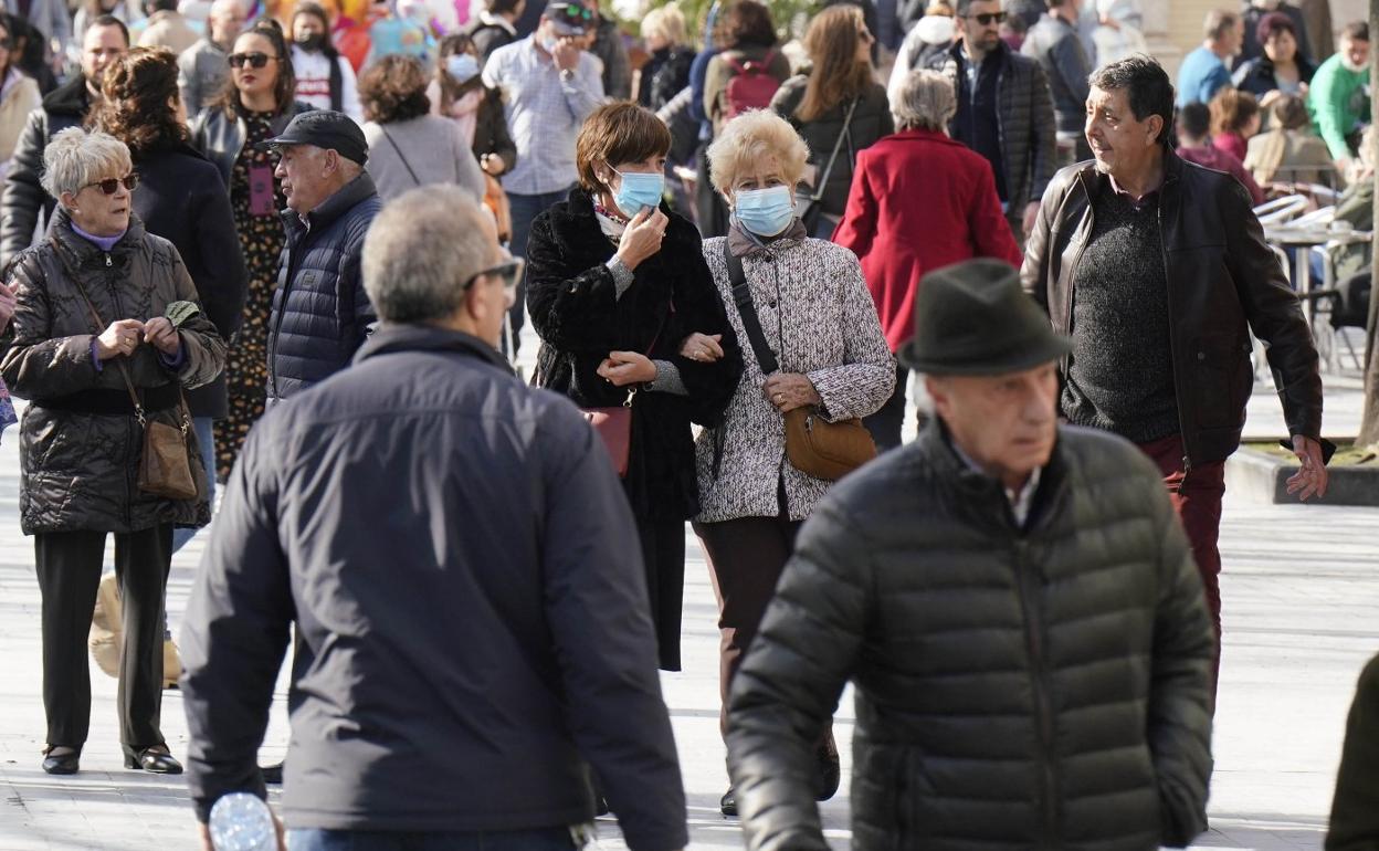 Paseantes con y sin mascarilla en una jornada de cielos despejados. 