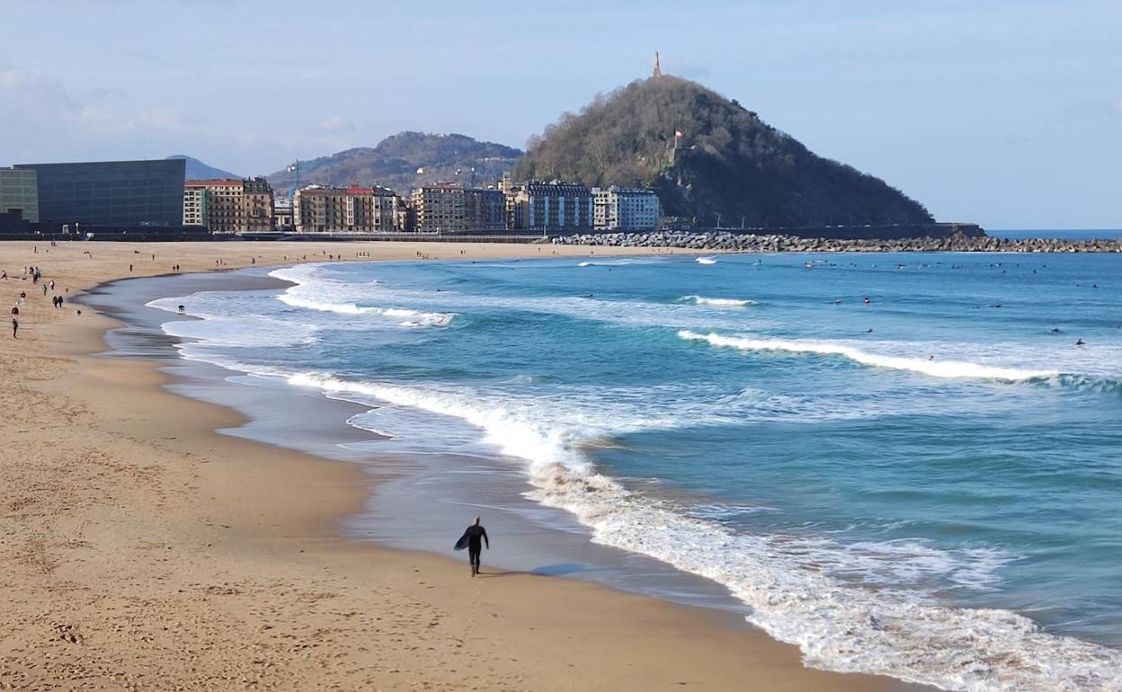 Paseantes y surfistas este domingo en la playa de Zurriola. 
