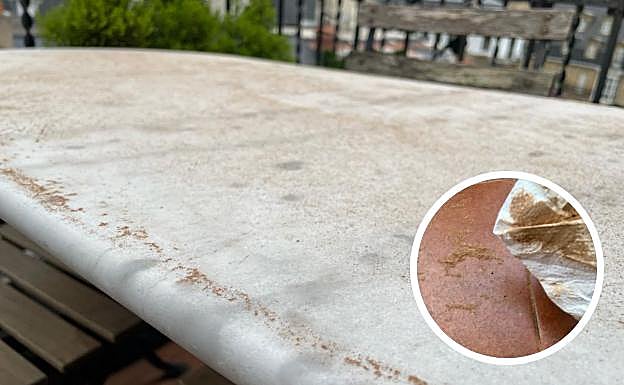 Una mesa en un balcón de Donostia y los restos de arena y polvo en el suelo.