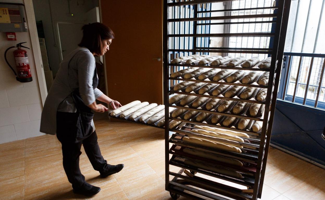 Una panadera coloca una bandeja con barras en un carro en su panadería de Irun. 
