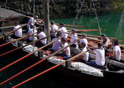 Imagen secundaria 1 - Irurzun, Olano, Agote y Alberdi en la presentación de la travesía en el muelle donostiarra.. Los remeros. Una mujer en el cartel anunciador.