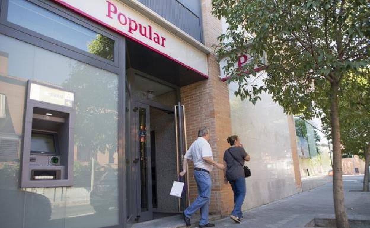 Dos personas salen de una oficina del Banco Popular.