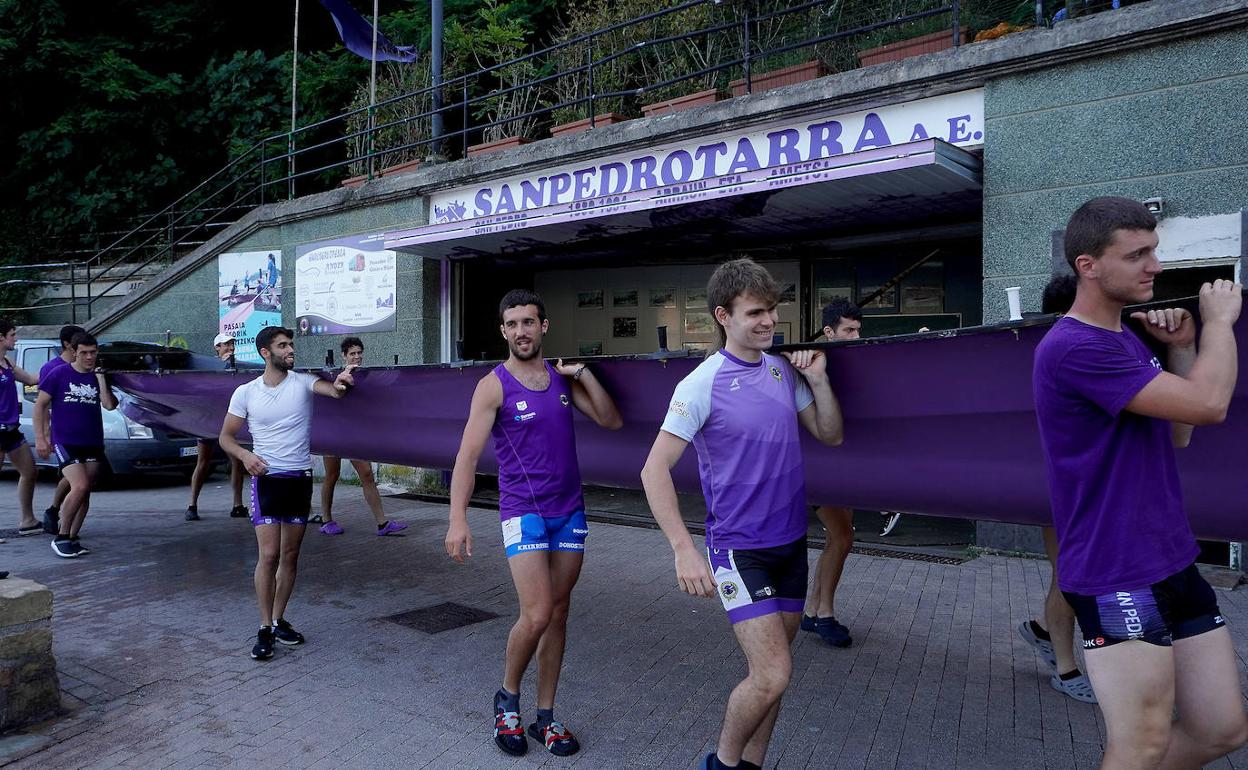 Los remeros de San Pedro portan la trainera para salir al agua a entrenar. 