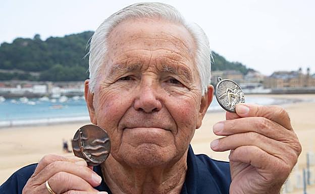 Imagen principal - Arriba, Carlos Santana con las medallas de las dos primeras ediciones de la Getaria - Zarautz. Abajo uno de los muchos textos publicados sobre las hazañas del nadador. Carlos Santana sigue nadando todos los días a sus 82 años. 