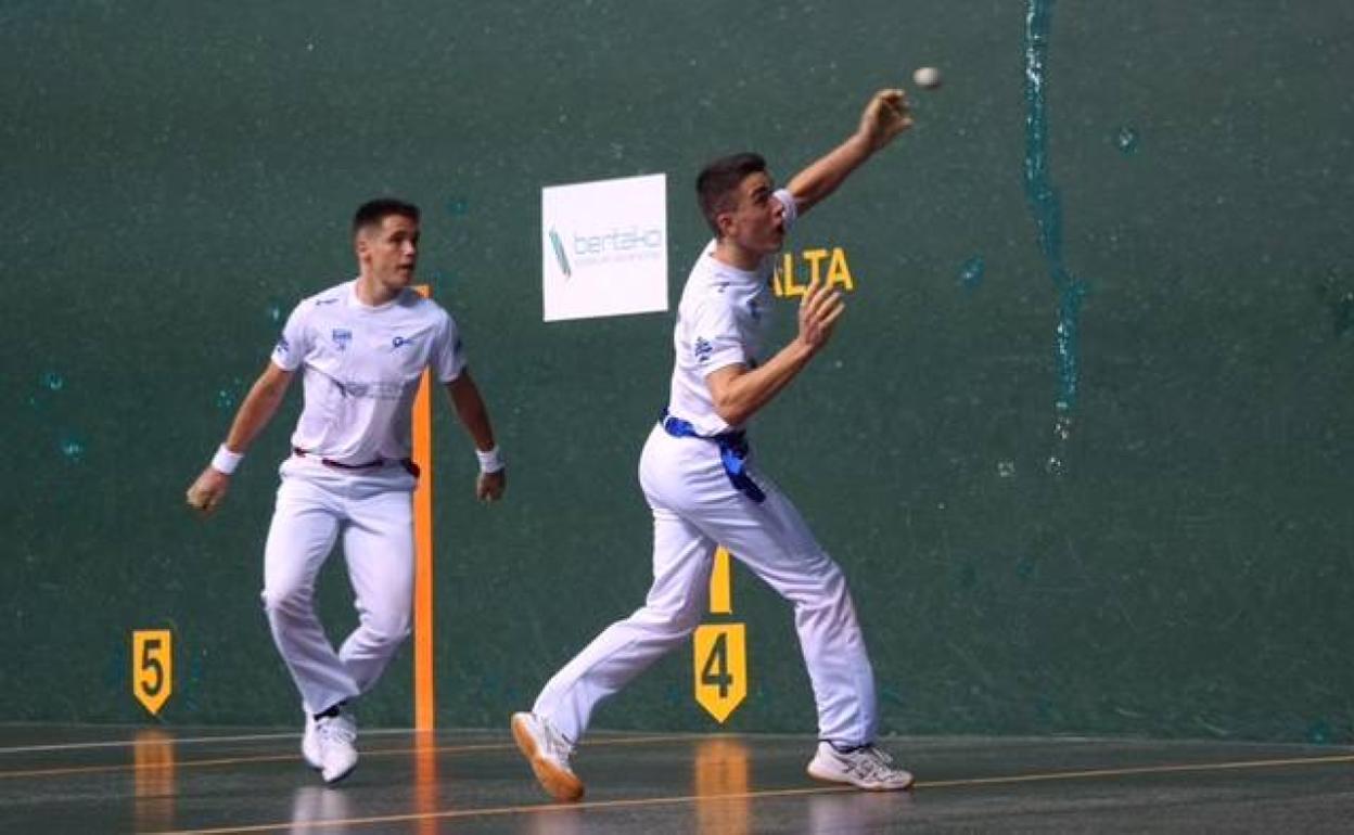Uno de los pelotaris engancha una bolea con la izquierda.