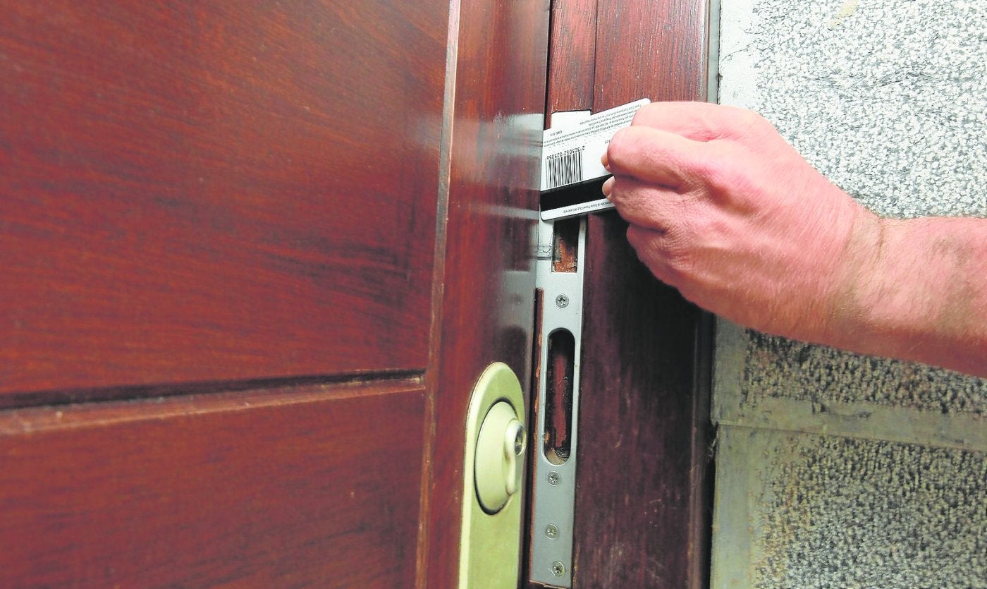 Un hombre abre la puerta de un domicilio con una tarjeta. 