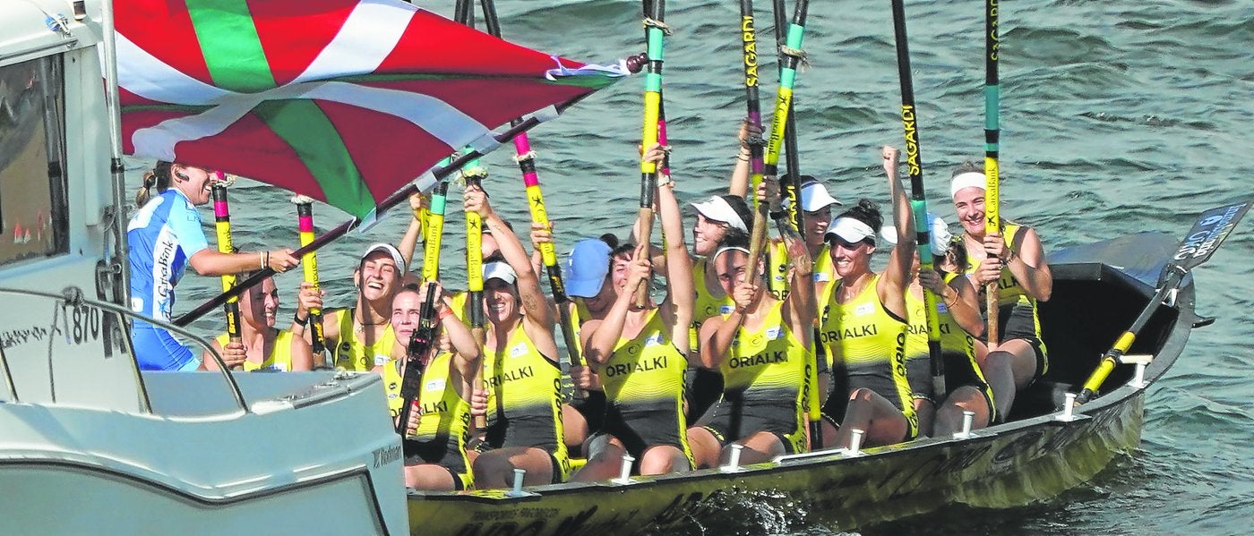 Nadeth Agirre ondea la bandera conquistada en Getxo mientras lasremeras levantan los remos.