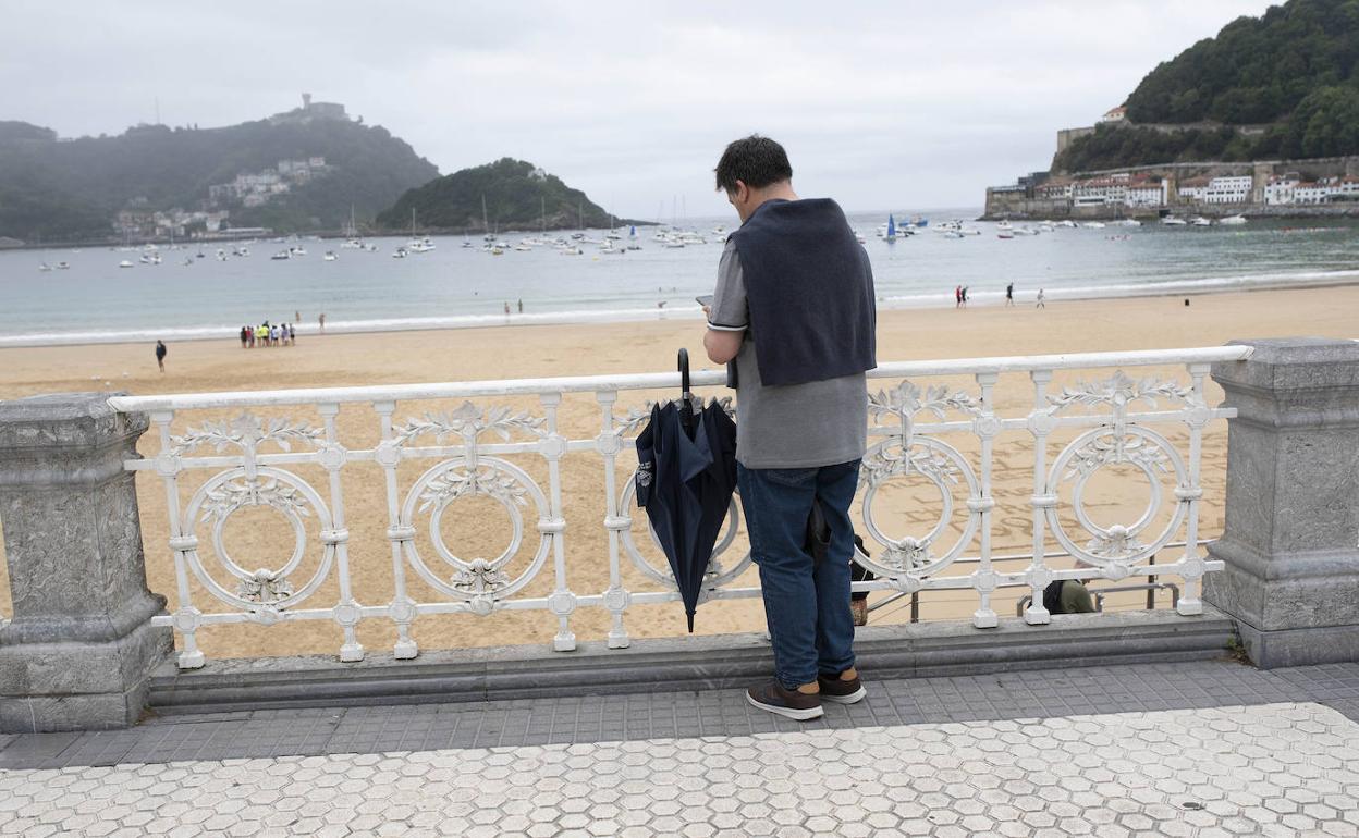 Un hombre cuelga su paraguas de la barandilla de La Concha. Fue el pasado 4 de julio.
