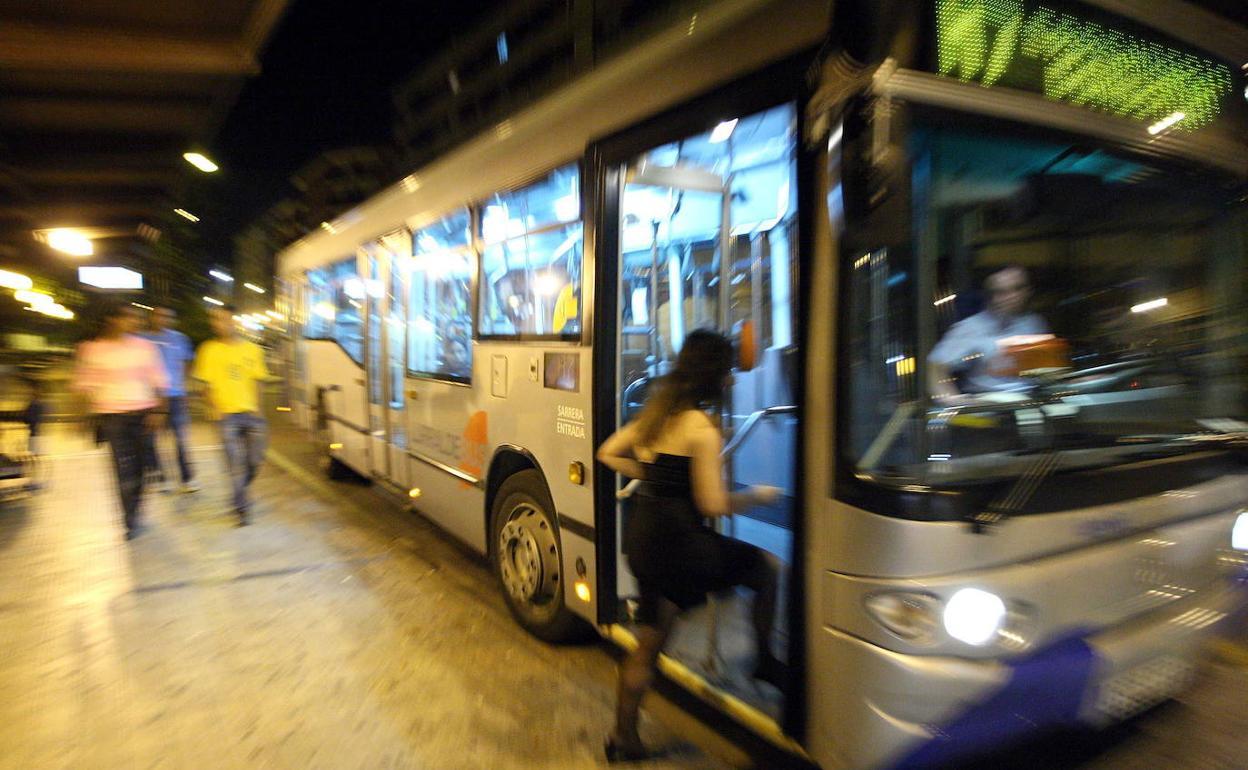 Una mujer sube por la noche a un autobús.