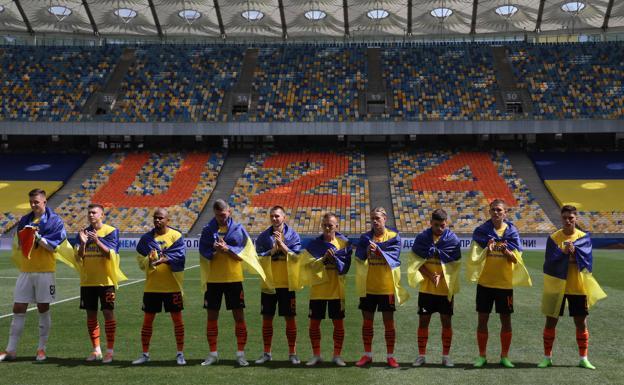 Shakhtar y Metalist salen al campo con la bandera ucraniana mientras escuchan el himno nacional. 