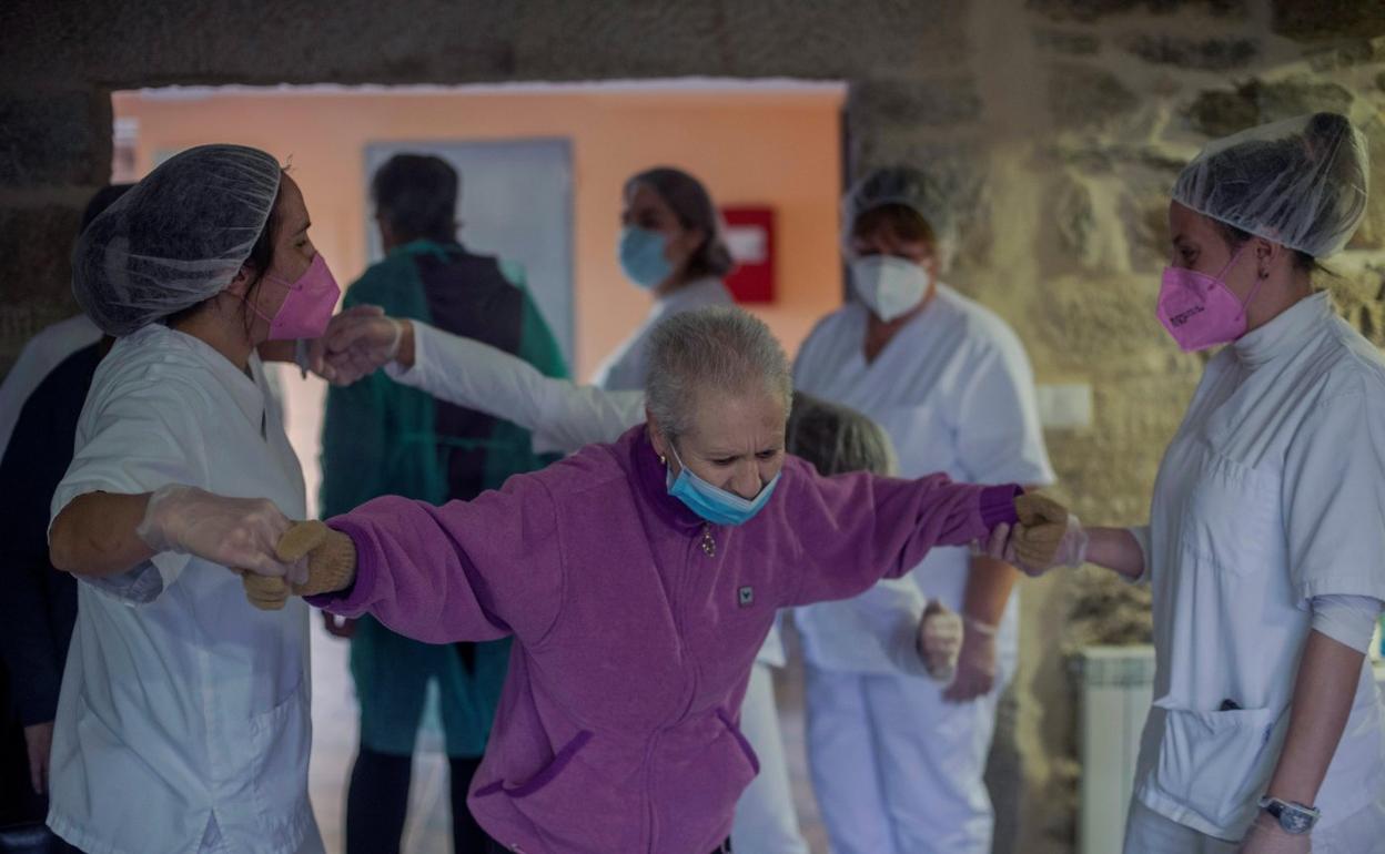 Dos trabajadoras ayudan a una residente en un centro de mayores. 